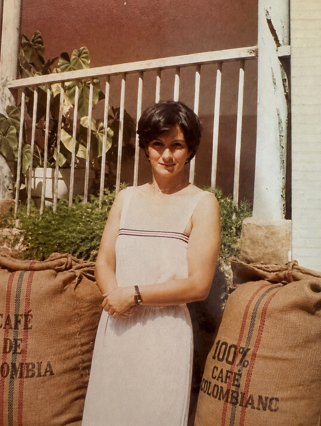 Margarita, the grandmother who inspires Madrigal, standing beside sacks of Colombian coffee